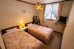 a bedroom with two beds and a window at ピュアモール ミモザ in Hakuba