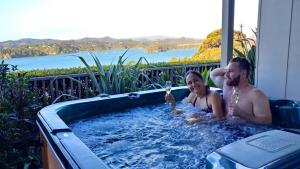 two people in a hot tub with a view of the water at Tarlton's Lodge in Paihia