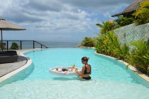 a woman in a swimming pool with a tub in the water at La Joya Biu Biu Resort - CHSE Certified in Jimbaran