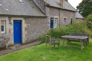 une table de pique-nique et un banc devant un bâtiment dans l'établissement Laundry Cottage, à Lanark 7 autres photos