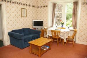 ein Wohnzimmer mit einem blauen Sofa und einem Tisch in der Unterkunft Laundry Cottage in Lanark