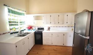 a kitchen with white cabinets and a black refrigerator at Fitzy Haven in Gros Islet