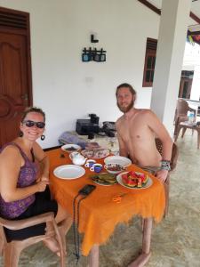 a man and a woman sitting at a table with food at Disna Place in Unawatuna