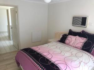 a bedroom with a bed with a pink and black comforter at Relaxed Ocean View in Mandurah