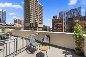 a balcony with chairs and tables and a city skyline at YEHS Hotel Sydney QVB in Sydney