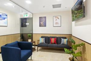 una sala de espera con 2 sillas y un sofá en YEHS Hotel Sydney QVB, en Sídney