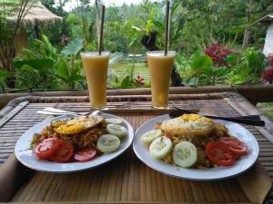 two plates of food on a table with two glasses of beer at Second Home Bungalows in Tetebatu