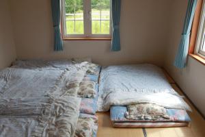 a bedroom with two beds sitting next to a window at Farm Inn Tsurui in Tsurui