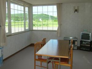 ein Esszimmer mit einem Tisch, Stühlen und Fenstern in der Unterkunft Farm Inn Tsurui in Tsurui