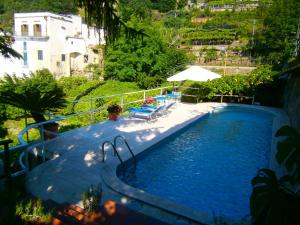 a large swimming pool with an umbrella and chairs at Villa En Rose in Ravello