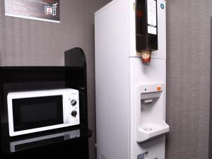 a white refrigerator with a microwave on top of it at APA Hotel & Resort Yokohama Bay Tower in Yokohama