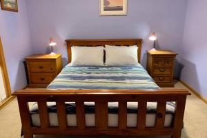 a bedroom with a wooden bed with two night stands at Leeward 'tranquil beachfront' in Kingscote
