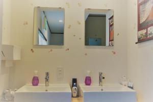 a bathroom with two sinks and two mirrors at Hana Hostel Fujisan in Fujiyoshida