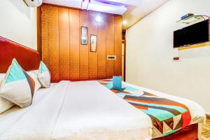 een slaapkamer met een groot wit bed en een flatscreen-tv bij FabHotel Gazal Residency Mahanagar in Lucknow