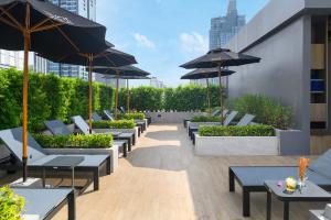 a patio with tables and chairs and umbrellas at Eleven Bangkok Sukhumvit 11 by Kingston Hotels in Bangkok