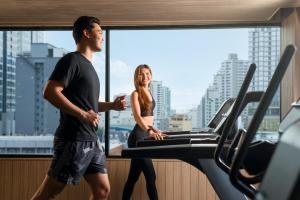 a man and a woman on a treadmill in a gym at Eleven Bangkok Sukhumvit 11 by Kingston Hotels in Bangkok