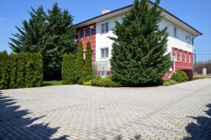 a house with trees in front of a driveway at Hotel Weldi in Győr