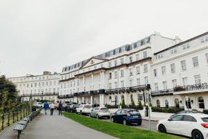 a row of white buildings with parked cars on a street at Crown Spa Hotel Scarborough by Compass Hospitality in Scarborough