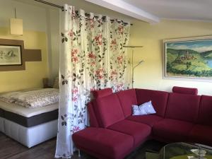 ein Wohnzimmer mit einer roten Couch und einem Bett in der Unterkunft Moselnest in Cochem