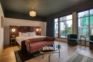 a hotel room with a bed and a couch and windows at The Chow Kit - an Ormond Hotel in Kuala Lumpur