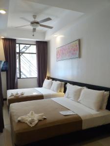 a hotel room with two beds and a ceiling fan at One Crescent Place Hotel in Boracay