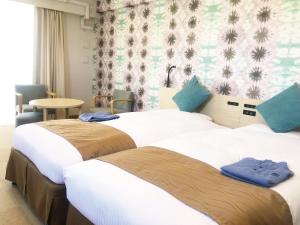 2 Betten in einem Hotelzimmer mit blauen Handtüchern darauf in der Unterkunft La'gent Hotel Okinawa Chatan Hotel and Hostel in Chatan