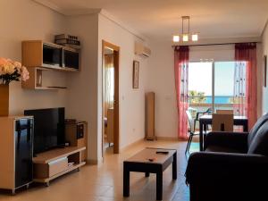 ein Wohnzimmer mit einem Sofa und einem TV in der Unterkunft Frontal en primera linea Vistamar 3 in Oropesa del Mar