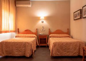 a hotel room with two beds and a table at Hotel La Zambra in Mancha Real
