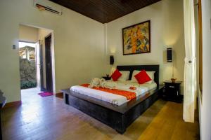 a bedroom with a large bed with red pillows at The Galuh Pekutatan in Pulukan