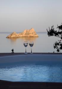 two wine glasses sitting on the edge of a swimming pool at Krinakia Villas in Xerokampos