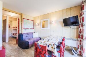 a room with a bed and a tv and a table at Residence Les Brigues - maeva Home in Courchevel