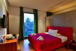a bedroom with a red bed and a desk and a window at Arthotel & Park Lecce in Lecce