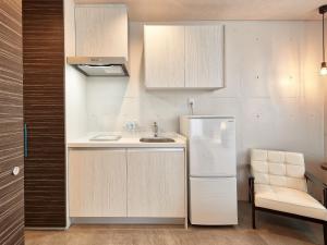 a kitchen with a sink and a refrigerator at Yomitan Condhotel ND in Yomitan