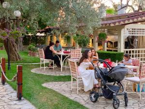 a woman sitting at a table with a baby stroller at PalmaNova Resort in Tirana