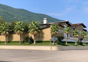 a house with palm trees in front of a mountain at PalmaNova Resort in Tirana