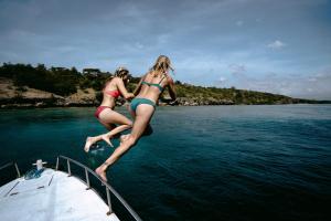 two girls jumping off of a boat in the water at Menjangan Dynasty Resort in Banyuwedang