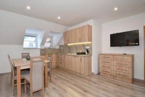 a kitchen with a table and a television on the wall at Chata PELC in Stratená