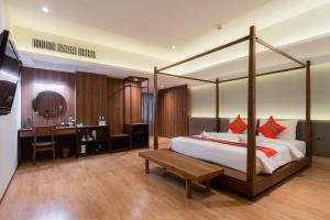 een slaapkamer met een hemelbed, een bureau en een tafel bij True Siam Phayathai Hotel in Bangkok