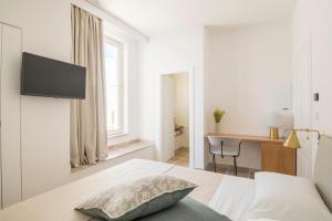 a white bedroom with a bed and a desk at Palazzo Mulini in Monopoli