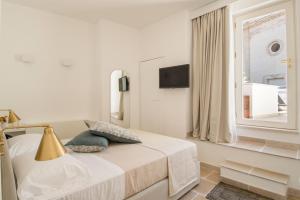 a white bedroom with a bed and a window at Palazzo Mulini in Monopoli