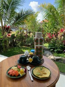 a wooden table with two plates of fruit on it at Cenik House Ubud in Ubud