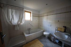 een badkamer met een bad, een toilet en een wastafel bij Appartements Spielberg in Leogang