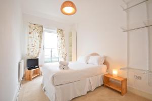 een witte slaapkamer met een bed en een televisie bij Town or Country - Splash B in Southampton