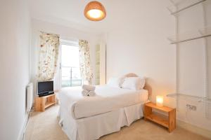 a white bedroom with a bed and a television at Town or Country - Splash B in Southampton