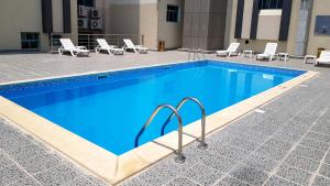 a large swimming pool with chairs and a table at Al Muntazah Plaza Hotel in Doha