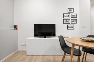 un salon avec une table et une télévision sur un mur blanc dans l'établissement Piazza Maggiore White Apartment, à Bologne