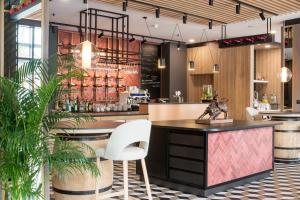 a restaurant with a bar with white chairs and plants at ibis Styles Kraków East in Kraków