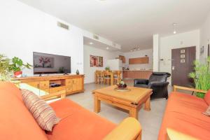 sala de estar con sofá naranja y mesa en Family-Friendly Apartment in Zichron Yaakov, en Zikhron Ya‘aqov