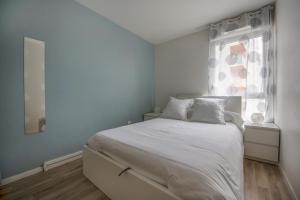a bedroom with a white bed and a window at Appartements de 2 ou 3 chambres à 40 minutes de Paris in Evry-Courcouronnes