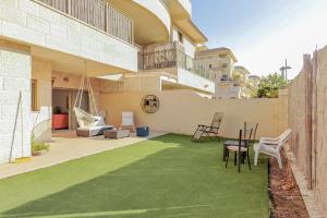 a patio with a green lawn in front of a building at Family-Friendly Apartment in Zichron Yaakov in Zikhron Ya'akov